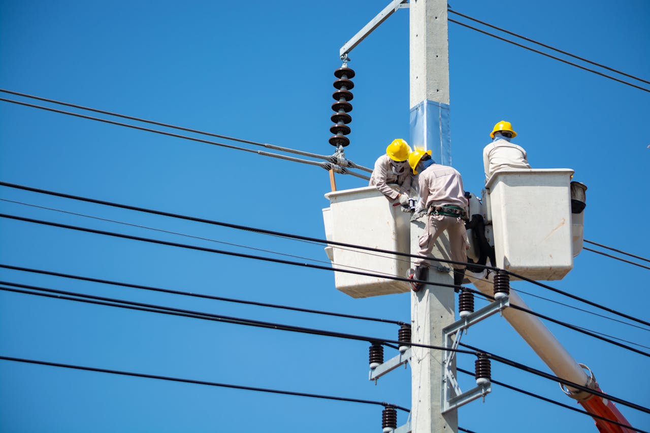 Electricians wearing safety gear work on power lines in Nakhon Ratchasima, Thailand.